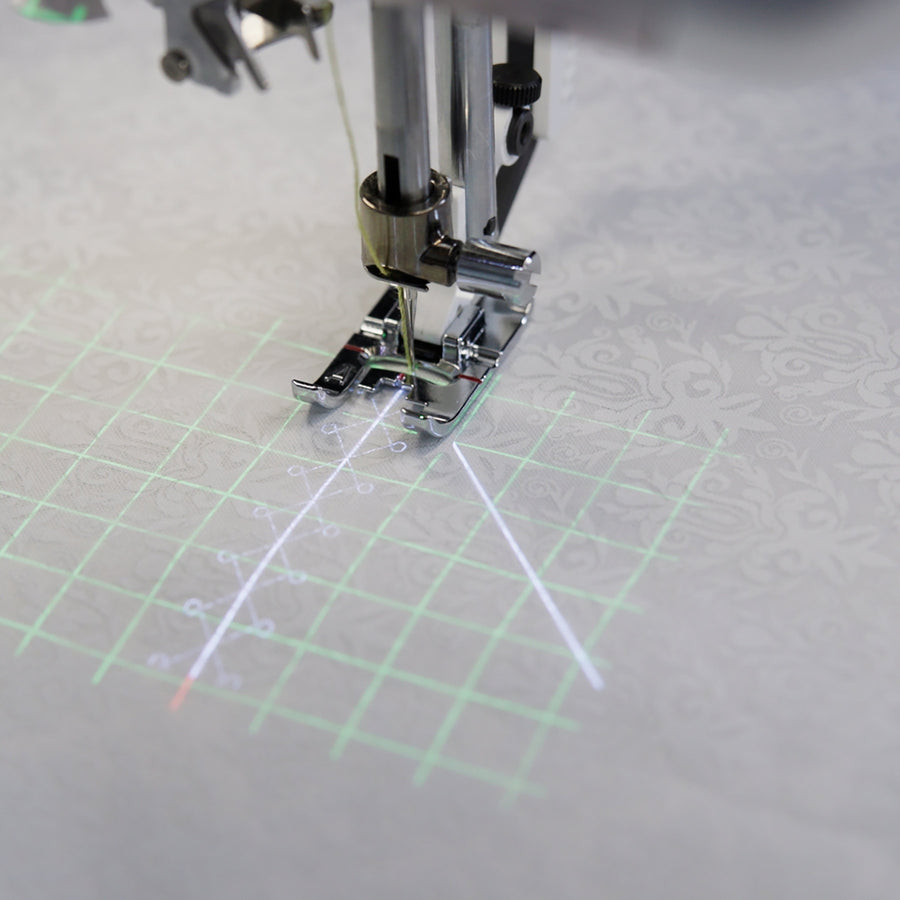 Projected sewing grid and stitch guidance on fabric beside the Designer Epic 3 presser foot