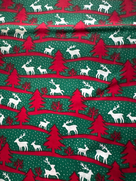 Árboles navideños de estilo vintage, renos y líneas sinuosas sobre fondo verde. 100 % algodón ligero. Precio por yarda.