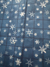 Motivos vintage de copos de nieve sobre fondo azul a cuadros. 100 % algodón ligero. Precio por yarda.