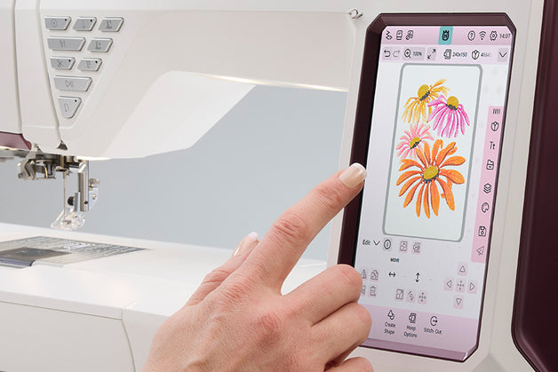 Person using a digital embroidery machine with a screen displaying floral designs.