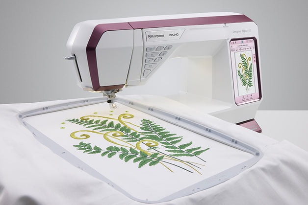 Embroidery machine with a floral design on a white fabric