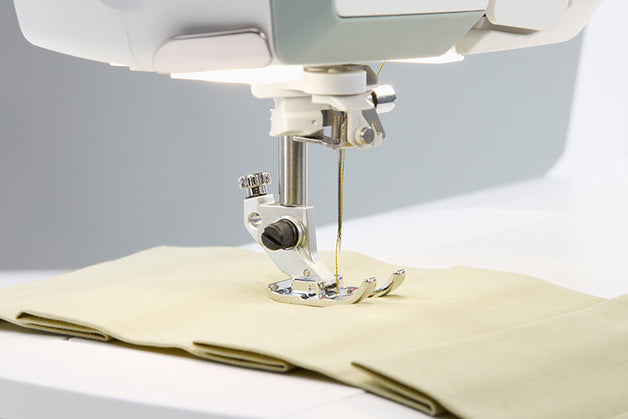 Primer plano de una aguja de máquina de coser en acción sobre la tela.